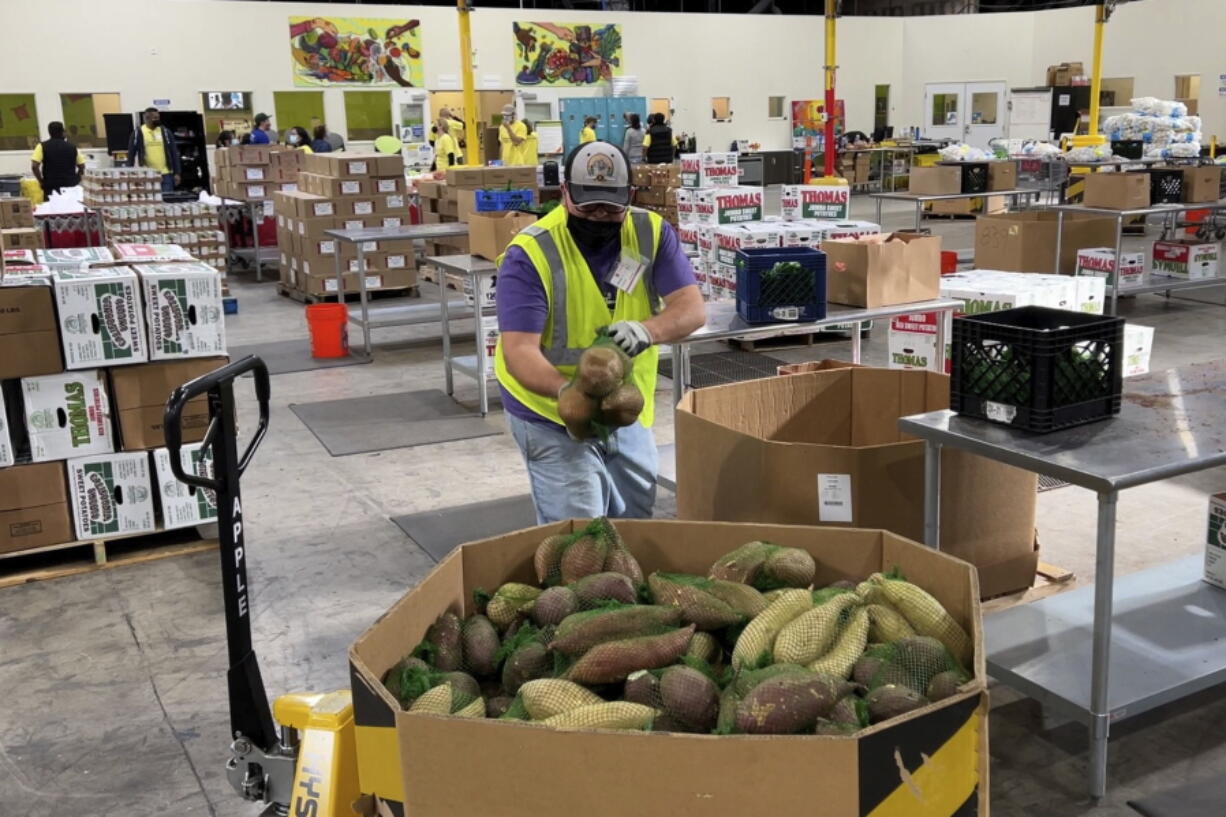 A worker puts bags of sweet potatoes in a container in the warehouse of the Alameda County Community Food Bank in Oakland, Calif., on Nov. 5, 2021. U.S. food banks dealing with increased demand from families sidelined by the pandemic now face a new challenge - surging food prices and supply chain issues. As holidays approach, some food banks worry they won't have enough turkeys, stuffing and cranberry sauce for Thanksgiving and Christmas.