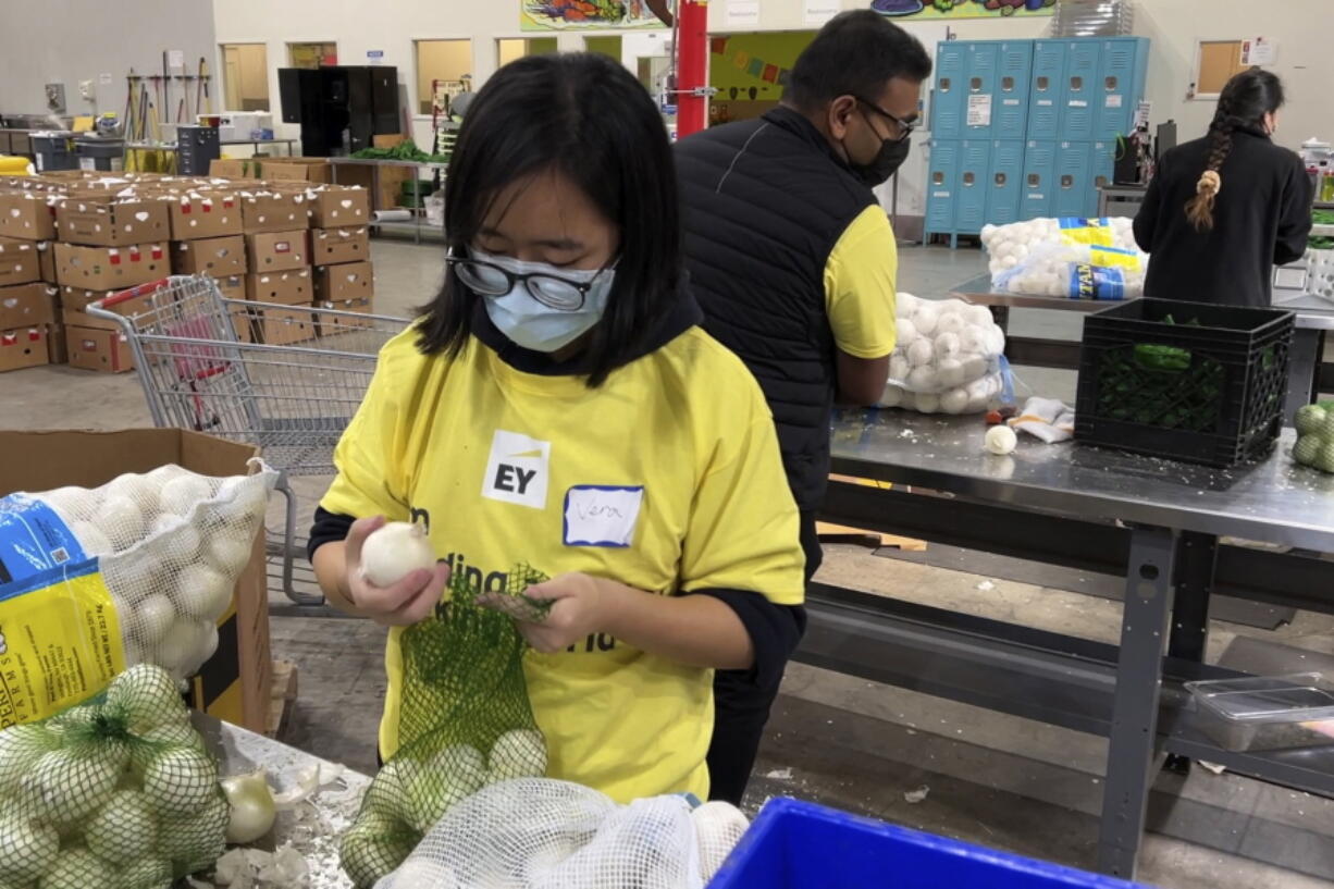 A volunteer packs onions in the warehouse of the Alameda County Community Food Bank in Oakland, Calif., on Nov. 5, 2021. U.S. food banks dealing with increased demand from families sidelined by the pandemic now face a new challenge - surging food prices and supply chain issues. As holidays approach, some food banks worry they won't have enough turkeys, stuffing and cranberry sauce for Thanksgiving and Christmas. Residents picking up free groceries in Oakland said they're grateful for the extra help as the price of dairy, meat and fuel has shot up.