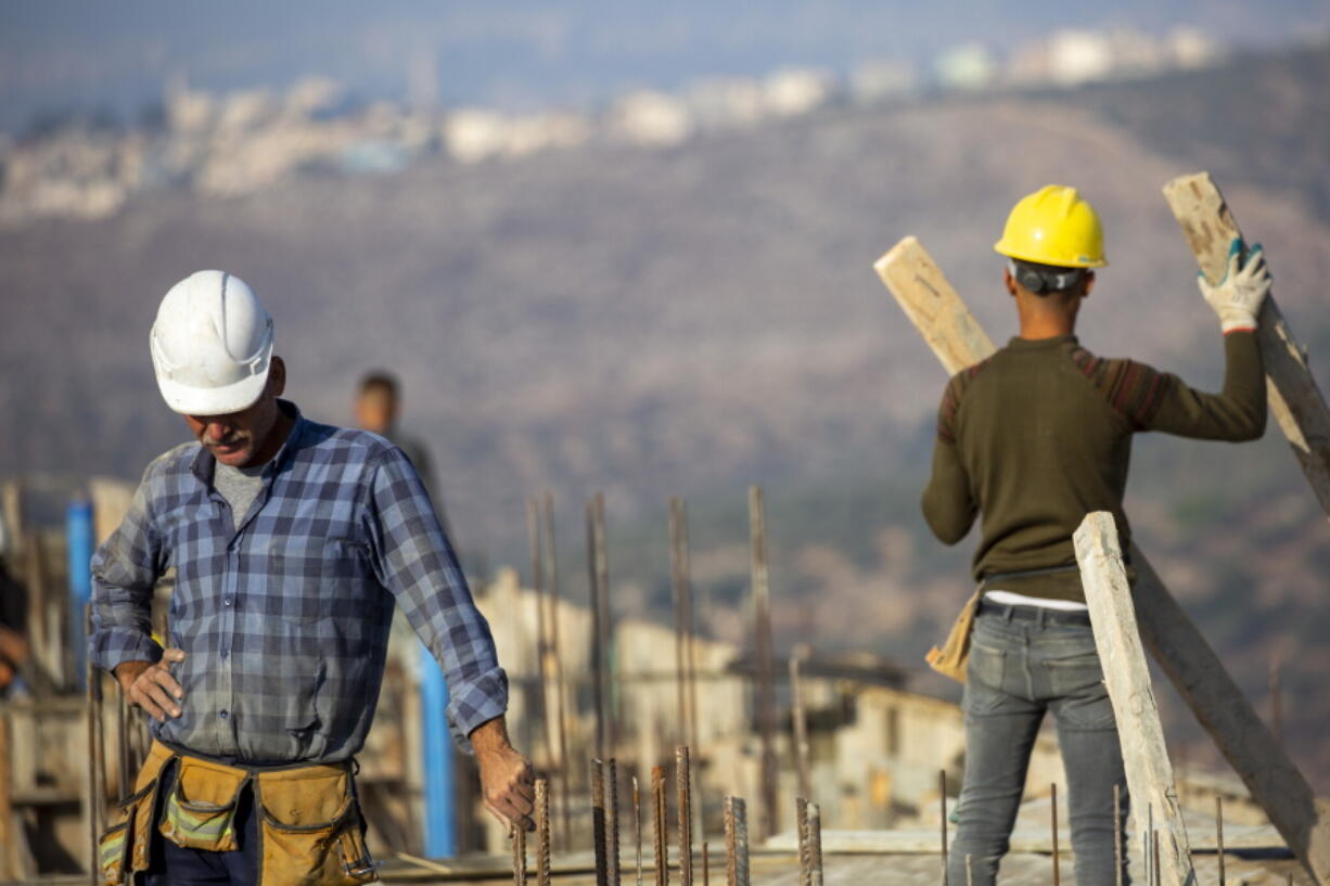 FILE - Palestinian laborers work building new houses in the West Bank Jewish settlement of Bruchin near the Palestinian town of Nablus, Monday, Oct. 25, 2021. After years in Israel's political wilderness, small dovish parties that support Palestinian statehood and oppose Jewish settlements are back in government. But they are finding their influence is limited, with pro-settler coalition partners showing little appetite for compromise and the country's decades-long occupation churning on.