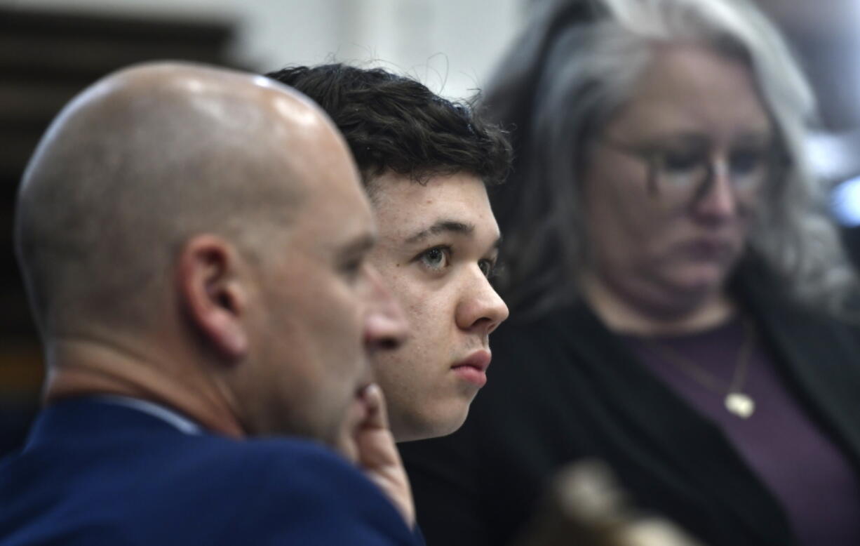 Kyle Rittenhouse, center, looks up and away from a video monitor as footage of him shooting on the night of Aug. 25, 2020, is shown during the trial at the Kenosha County Courthouse in Kenosha, Wis., on Wednesday, Nov. 3 2021.