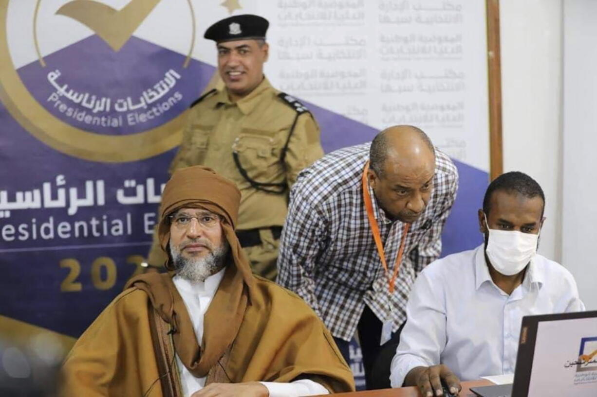 Seif al-Islam, left, the son and one-time heir apparent of late Libyan dictator Moammar Gadhafi registers his candidacy for the country's presidential elections next month, in Sabha, Libya, Sunday, Nov. 14, 2021. Al-Islam, who was seen as the reformist face of Gadhafi's regime before the 2011 uprising, was released in June 2017 after more than five years of detention.