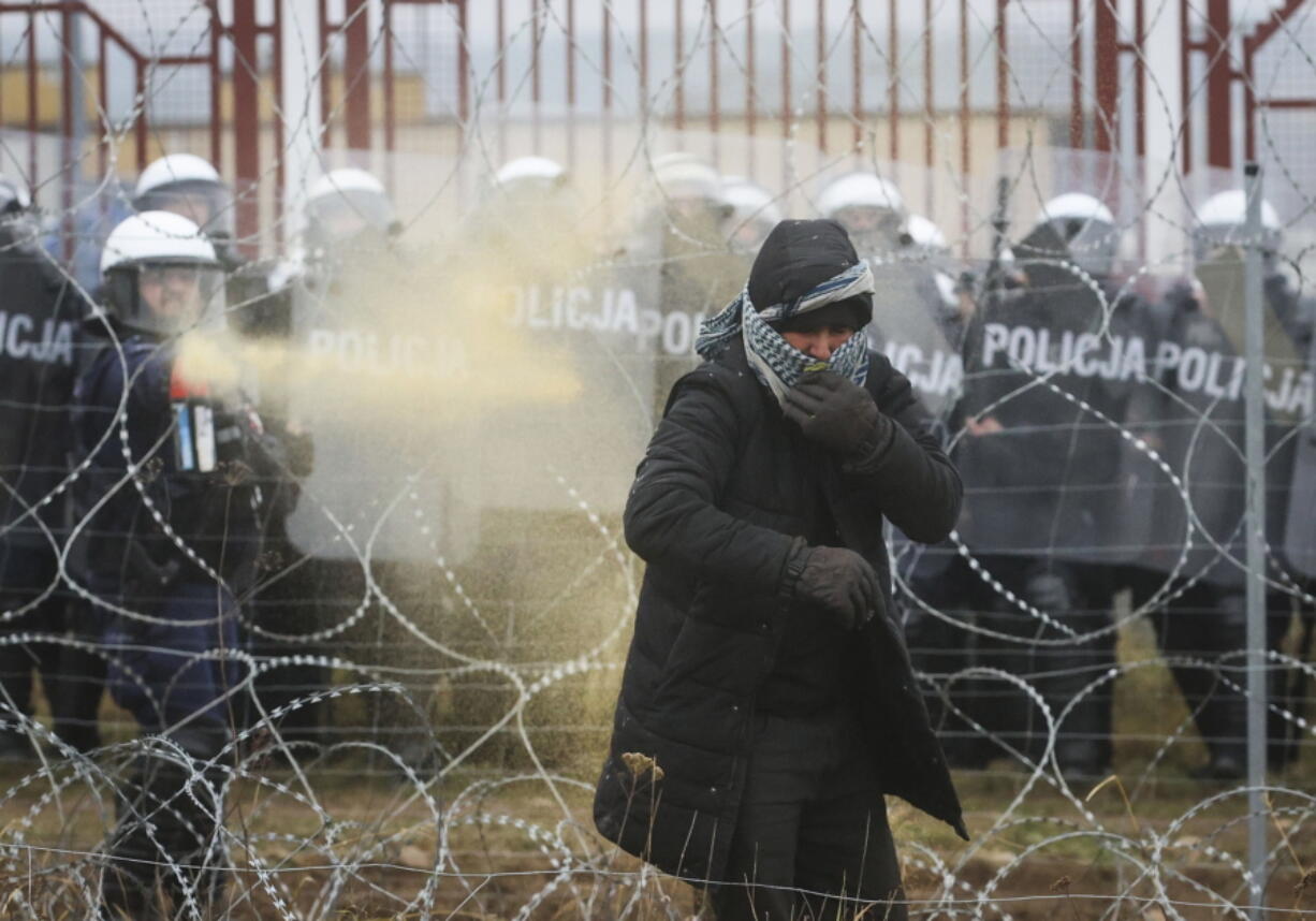 Polish serviceman sprays tear gas during clashes between migrants and Polish border guards at the Belarus-Poland border near Grodno, Belarus, on Tuesday, Nov. 16, 2021.