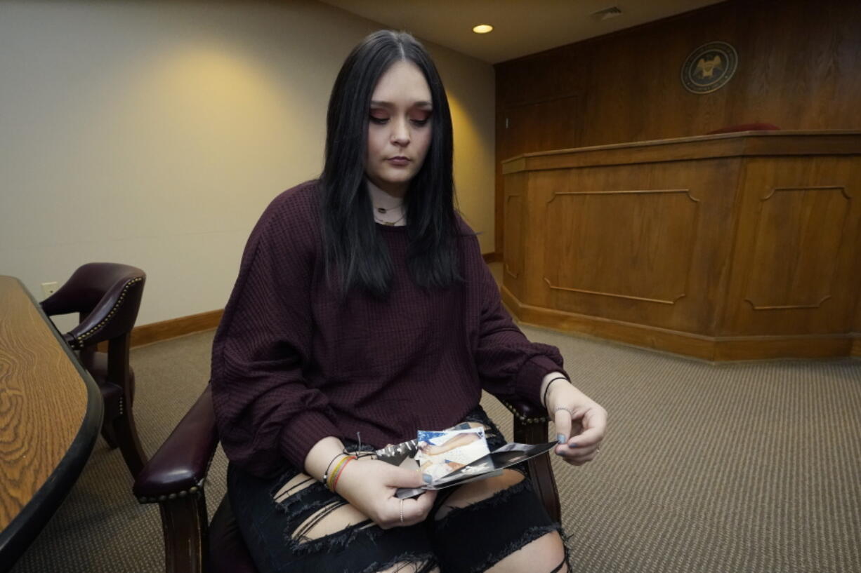 Lindsey Kirk looks at childhood photographs of herself and her late mother Kim Kirk Cox, Saturday, Nov. 13, 2021, in New Albany, Miss. She was 12 years old when her stepfather, David Neal Cox, terrorized her family, sexually assaulted her, and killed her mother, Kim Kirk Cox, in May 2010 at a home in Sherman, Miss. The Mississippi Supreme Court set an execution date of Wednesday, Nov. 17, 2021, for Cox after he said he wanted to surrender all appeals. (AP Photo/Rogelio V.