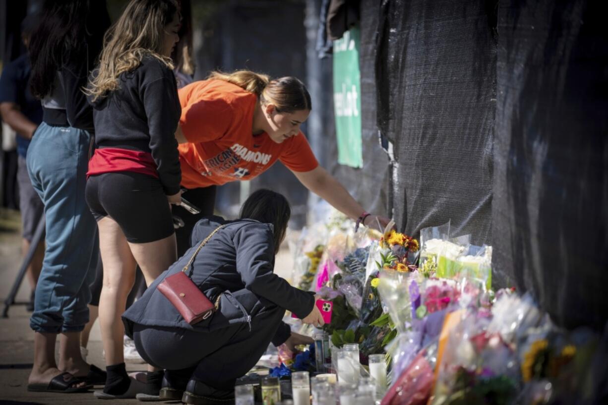 Stacey Sarmiento places flowers at a memorial in Houston on Sunday, Nov. 7, 2021 in memory of her friend, Rudy Pena, who died in a crush of people at the Astroworld music festival on Friday.