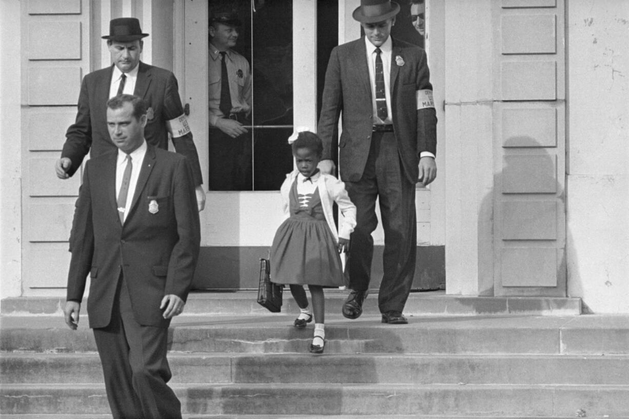 FILE - U.S. Deputy Marshals escort 6-year-old Ruby Bridges from William Frantz Elementary School in New Orleans, in this November 1960, file photo. New Orleans is marking the 61st anniversary of the integration of its public schools by four 6-year-old girls. Weekend events began with a Friday morning news conference at New Orleans City Hall and an evening screening of a video tribute to the four. A special church service and a motorcade are set for Sunday, Nov. 14, 2021.