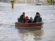 A woman and children who were stranded by high water due to flooding are rescued by a volunteer operating a boat in Abbotsford, British Columbia on Tuesday, Nov. 16, 2021. Officials in a small city near the Canada border are calling the damage devastating after a storm that dumped rain for days caused flooding and mudslides. City officials in Sumas, Washington said Tuesday that hundreds of people had been evacuated and estimated that 75% of homes had water damage. Just over the border, residents in about 1,100 rural homes in Abbotsford were told to evacuate as waterways started to rise quickly.