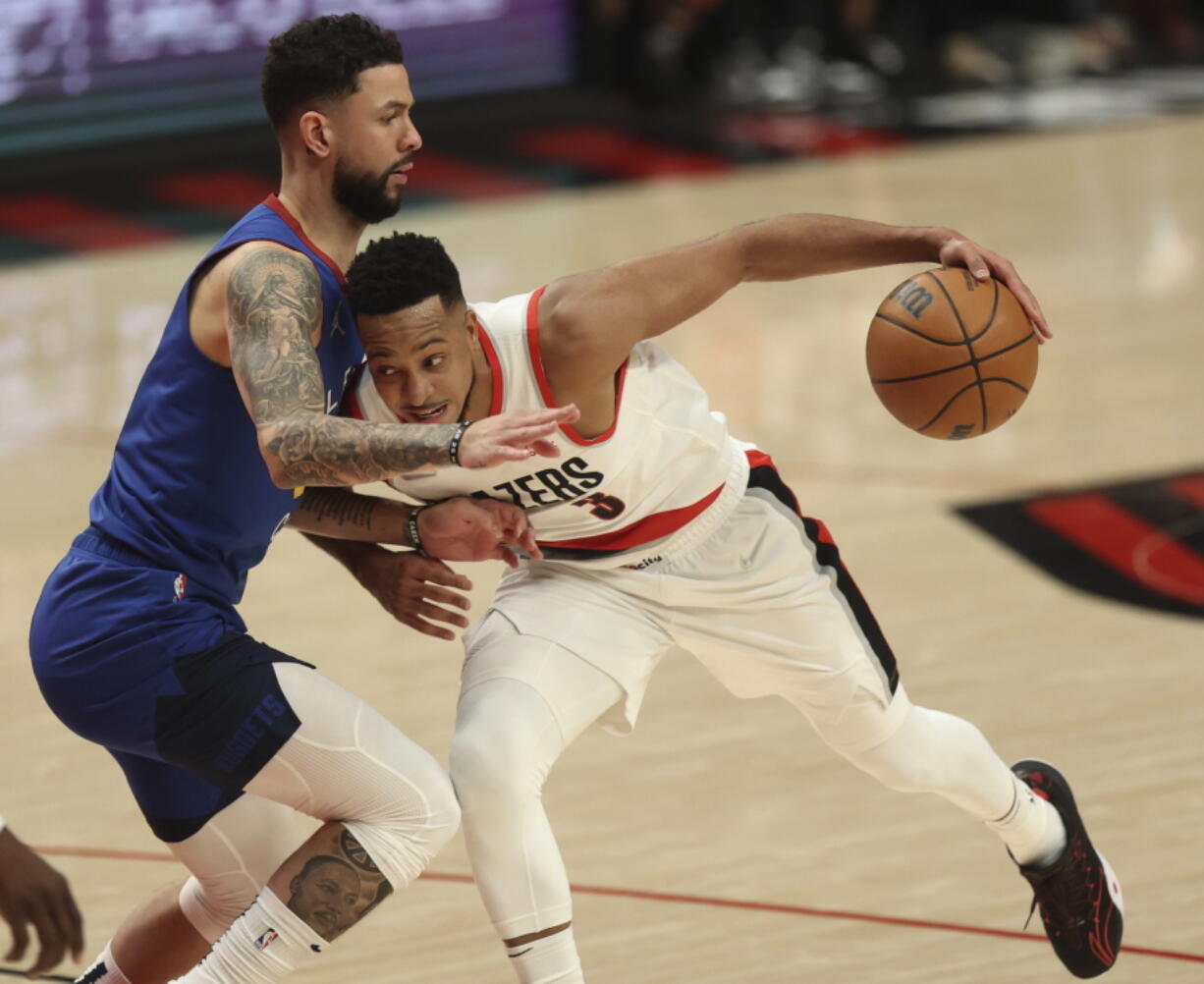 Portland Trail Blazers guard CJ McCollum, right, drives against Denver Nuggets guard Austin Rivers during the first half of an NBA basketball game in Portland, Ore., Tuesday, Nov. 23, 2021.