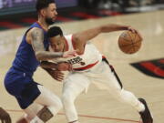 Portland Trail Blazers guard CJ McCollum, right, drives against Denver Nuggets guard Austin Rivers during the first half of an NBA basketball game in Portland, Ore., Tuesday, Nov. 23, 2021.