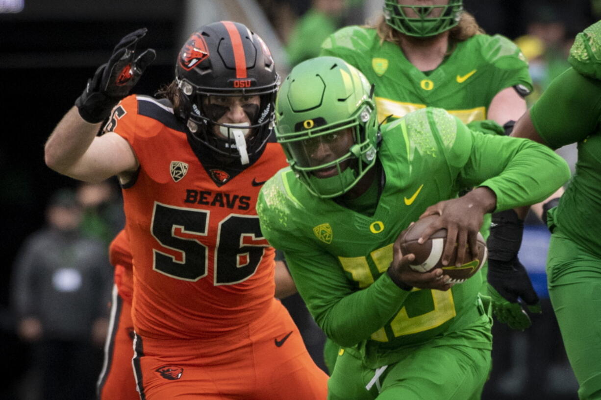 Oregon quarterback Anthony Brown (13) tries to elude the tackle of Oregon State linebacker Riley Sharp (56) during the second quarter of an NCAA college football game Saturday, Nov. 27, 2021, in Eugene, Ore.