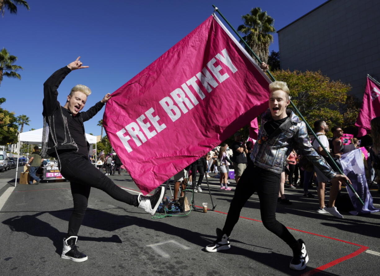 Twins Edward, right, and John Grimes of Dublin, Ireland, hold a "Free Britney" flag outside a hearing concerning the pop singer's conservatorship at the Stanley Mosk Courthouse, Friday, Nov. 12, 2021, in Los Angeles.