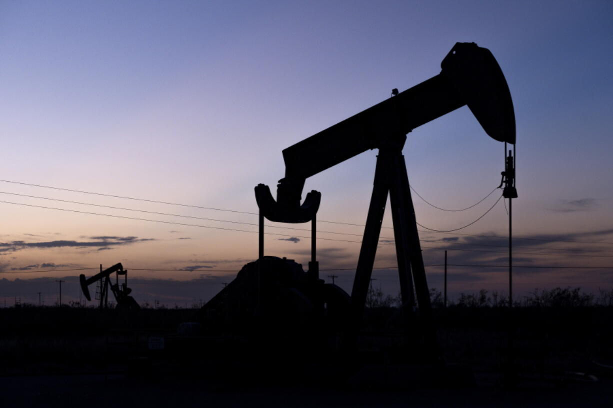 The hints of sunlight begin to disappear behind a pair of pumpjacks Wednesday, Sept. 15, 2021 in the oilfields of Penwell, Texas.  A movement to divest from fossil fuels is gaining momentum among foundations as activists push the $1 trillion sector to shift its money away from coal, oil and natural gas. The call from activists to the charitable world and other sectors has been simple: ditch fossil fuels and direct your investments into climate-friendly companies and funds.