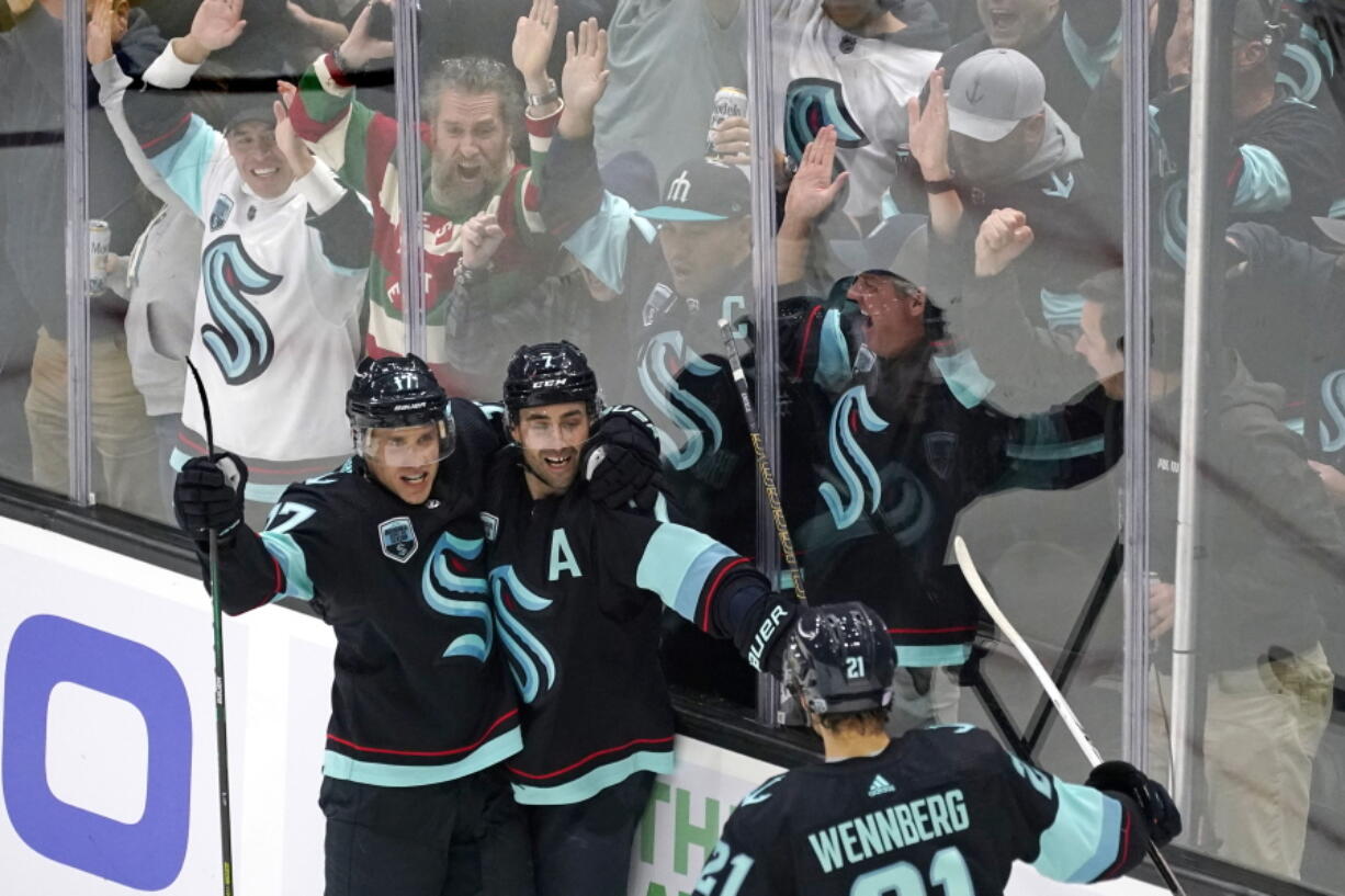 Fans cheer as Seattle Kraken's Jordan Eberle, center, is congratulated by teammates on his third goal of the night against the Buffalo Sabres,, during the third period of an NHL hockey game Thursday, Nov. 4, 2021, in Seattle.