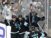 Fans cheer as Seattle Kraken's Jordan Eberle, center, is congratulated by teammates on his third goal of the night against the Buffalo Sabres,, during the third period of an NHL hockey game Thursday, Nov. 4, 2021, in Seattle.