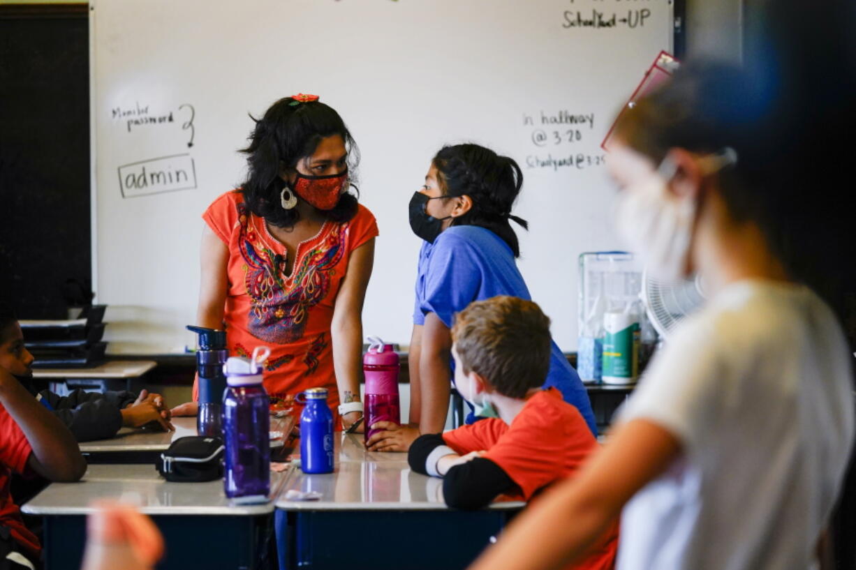 Student teacher Olivia Vazquez, standing, left, speaks with a student at the Eliza B. Kirkbride School in Philadelphia, Wednesday, Oct. 20, 2021. Vazquez is finishing up her last semester at Swarthmore College and hoping to help make sure immigrant students arriving in Philadelphia have a more supportive experience in school than she did growing up.