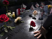 FILE - A firefighter places his hand on the name engravings on the south pool during ceremonies to commemorate the 20th anniversary of the Sept. 11 terrorist attacks, Sept. 11, 2021, at the National September 11 Memorial & Museum in New York. The FBI released hundreds of pages of newly declassified documents Wednesday, Nov. 3, about its long effort to explore connections between the Saudi government and the Sept. 11 attacks, revealing the scope of a strenuous but ultimately fruitless investigation whose outcome many question to this day.