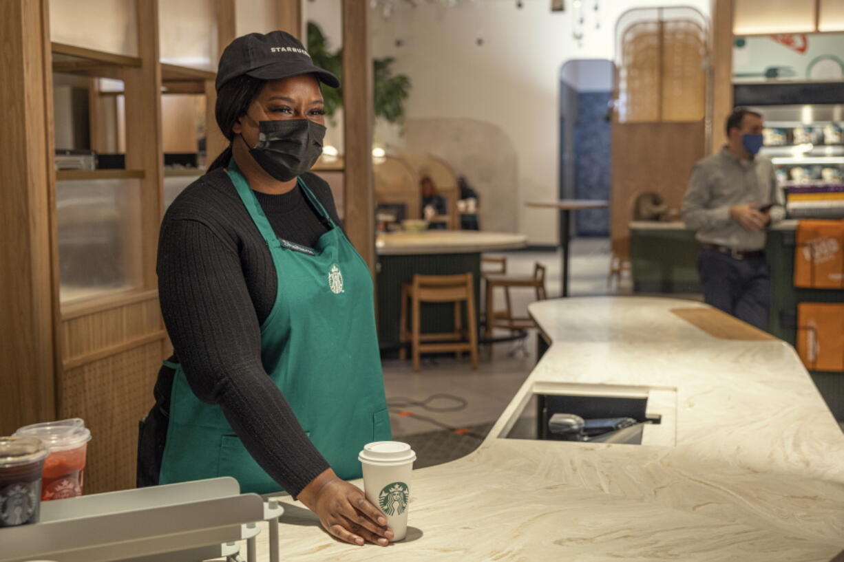 This photo provided by Starbucks shows a Starbucks employee with at order at a Amazon Go location. Starbucks and Amazon are teaming up on a grab-and-go store format. The Seattle-based companies will open their first Starbucks Pickup with Amazon Go location on Thursday, Nov.