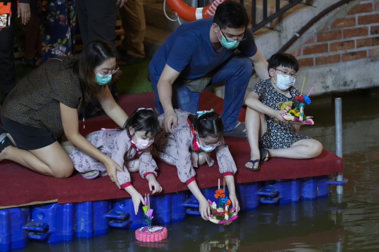 A Thai family places krathongs, small boats made of corn and decorated with banana leaves and flowers, into a Ong Ang canal during Loy Krathong festival in Bangkok, Thailand, Friday, Nov. 19, 2021. Thais believe that the candle-lit boats launched during the charming and popular Loy Krathong festival can carry the year's misfortunes away with them, but workers must clean up the waterways afterward to keep them from getting clogged and polluted.