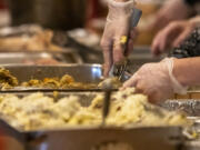 People scoop mashed potatoes, stuffing and other Thanksgiving staples into disposable tins at WareHouse '23 in Vancouver last year.