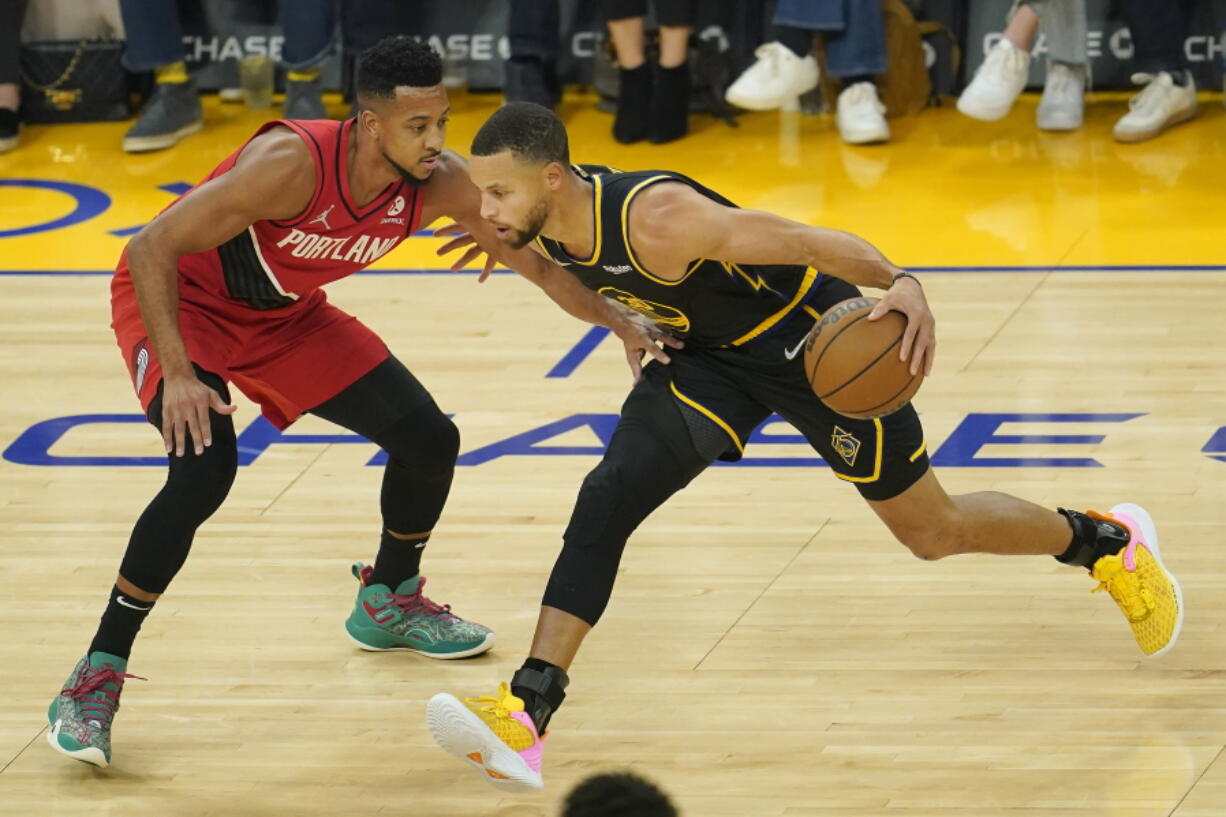 Golden State Warriors guard Stephen Curry, right, drives to the basket against Portland Trail Blazers guard CJ McCollum during the first half of an NBA basketball game in San Francisco, Friday, Nov. 26, 2021.