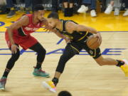 Golden State Warriors guard Stephen Curry, right, drives to the basket against Portland Trail Blazers guard CJ McCollum during the first half of an NBA basketball game in San Francisco, Friday, Nov. 26, 2021.