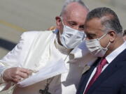 FILE - Pope Francis is greeted by Iraqi Prime Minister Mustafa al-Kadhimi as he arrives at Baghdad's international airport, Iraq, on March 5, 2021. Pope Francis is condemning the assassination attempt against Iraq's prime minister as a "vile act of terrorism" and says he is praying for peace in the country. The Vatican secretary of state, Cardinal Pietro Parolin, sent a telegram Tuesday to Prime Minister Mustafa al-Kadhimi expressing Francis' solidarity and prayers to al-Kadhimi's family and those injured in the drone attack on the prime minister's residence.