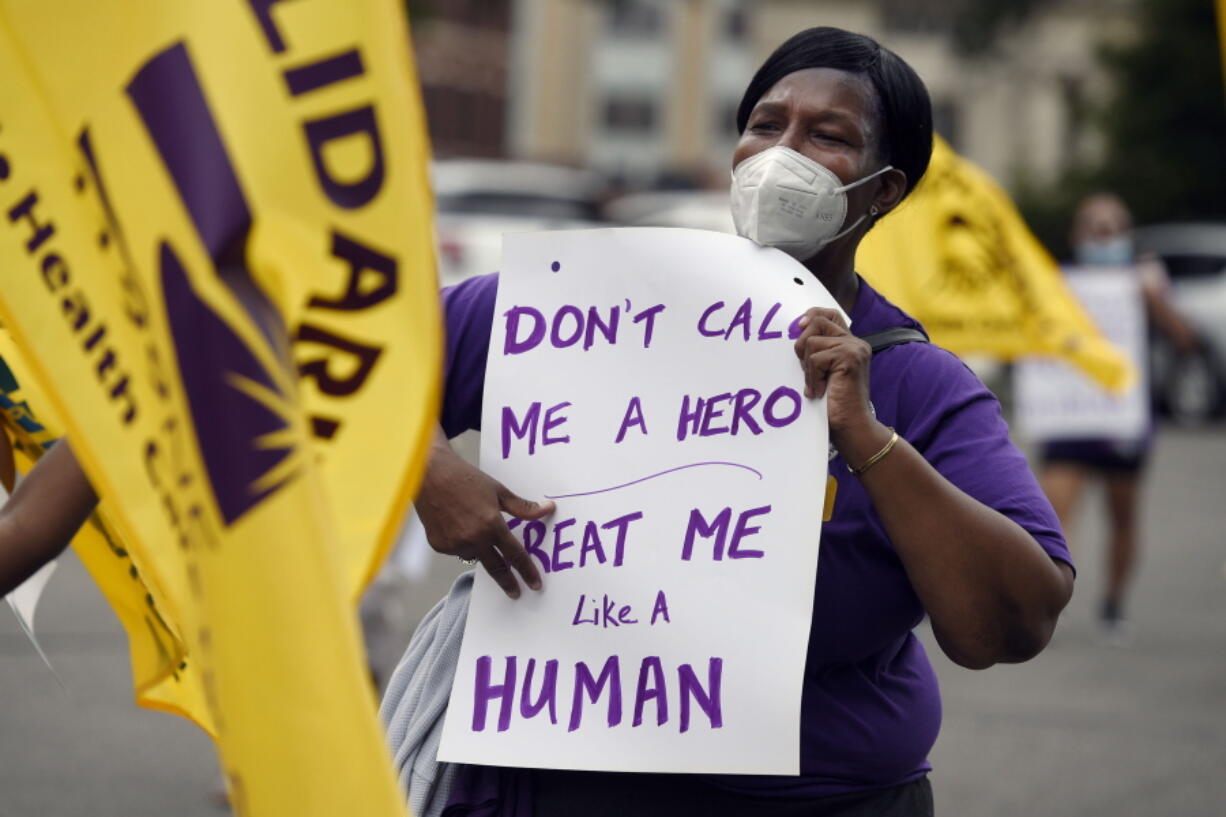 FILE - Clarissa Johnson of Hartford marches with long-term care members of the New England Health Care Employees Union, during a rally to demand new laws to protect long-term caregivers and consumers, July 23, 2020, at the State Capitol in Hartford, Conn. Connecticut essential state employees, who worked long hours during the COVID-19 pandemic, are still waiting for "hero pay" from $22.5 million in federal pandemic funds set aside in the state budget.