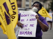 FILE - Clarissa Johnson of Hartford marches with long-term care members of the New England Health Care Employees Union, during a rally to demand new laws to protect long-term caregivers and consumers, July 23, 2020, at the State Capitol in Hartford, Conn. Connecticut essential state employees, who worked long hours during the COVID-19 pandemic, are still waiting for "hero pay" from $22.5 million in federal pandemic funds set aside in the state budget.