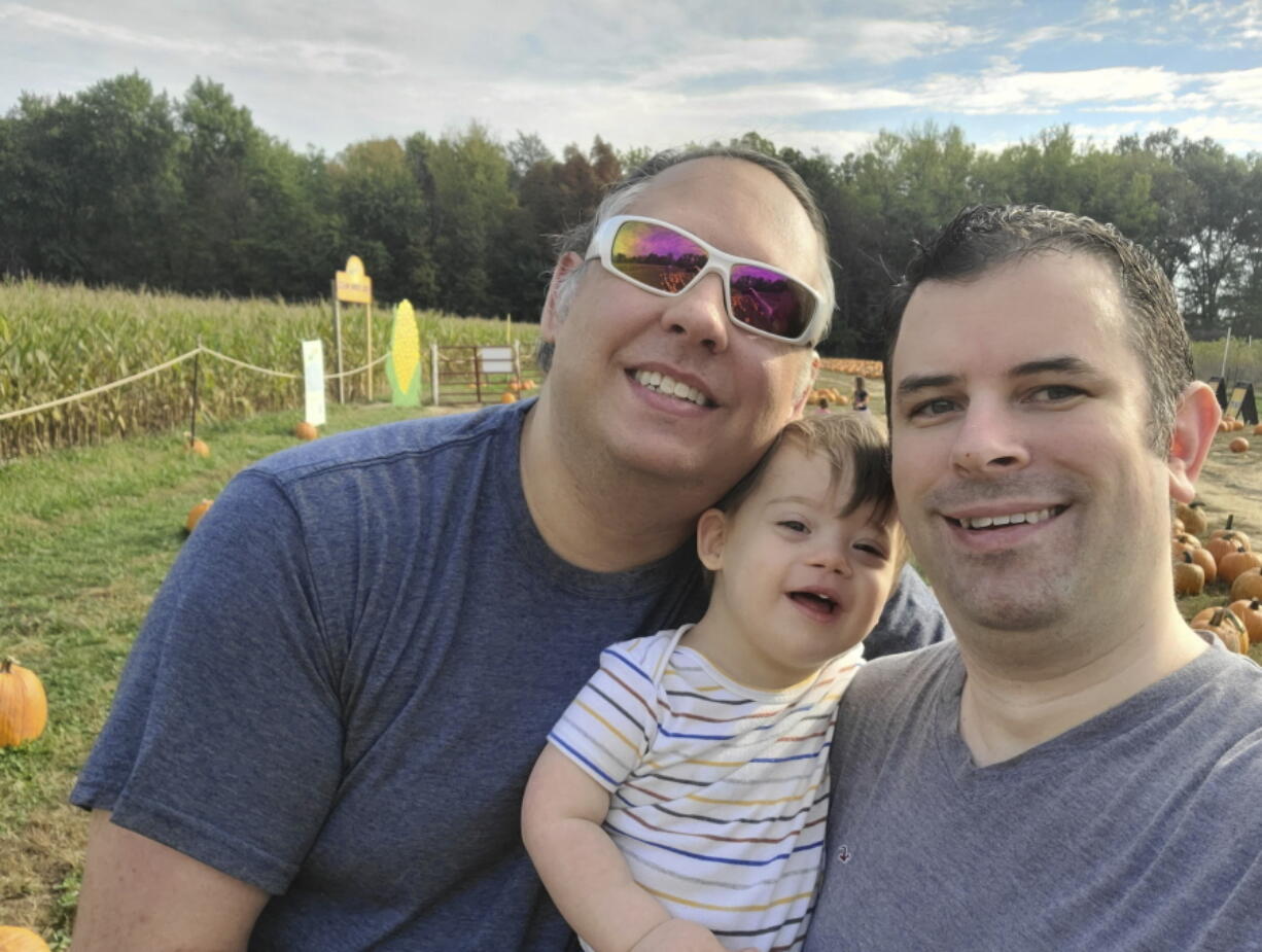 This photo shows Frederick Brushaber, left, his husband Mark Grice and their baby Freddie in Cincinnati, Ohio, on Oct. 15, 2021. The trio will spend Thanksgiving with family in Knoxville, Tenn.