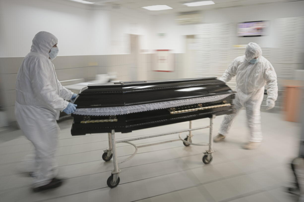 FILE - Funeral house employees drag a coffin on a trolley as they arrive at the University Emergency Hospital morgue to take a COVID-19 victim for burial, in Bucharest, Romania, Monday, Nov. 8, 2021. In much of Eastern Europe, coronavirus deaths are high and vaccination rates are low, but politicians have hesitated to impose the measures curb the virus that experts are calling for. A World Health Organization official declared earlier this month that Europe is again the epicenter of the coronavirus pandemic.