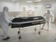 FILE - Funeral house employees drag a coffin on a trolley as they arrive at the University Emergency Hospital morgue to take a COVID-19 victim for burial, in Bucharest, Romania, Monday, Nov. 8, 2021. In much of Eastern Europe, coronavirus deaths are high and vaccination rates are low, but politicians have hesitated to impose the measures curb the virus that experts are calling for. A World Health Organization official declared earlier this month that Europe is again the epicenter of the coronavirus pandemic.