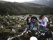 Relatives of Luis Enrique Rodriguez, who died of COVID-19, visit where he was buried on a hill at the El Pajonal de Cogua Natural Reserve, in Cogua, north of Bogota, Colombia, Monday, Oct. 25, 2021. Rodriguez died May 14, 2021. Relatives bury the ashes of their loved ones who died of coronavirus and plant a tree in their memory.