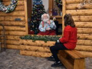 Santa, Sid Fletcher, sits behind a glass barrier as he hears Kendra Alexander of St. James, Minn., during her visit Nov. 15 at The Santa Experience at the Mall of America in Bloomington, Minn.