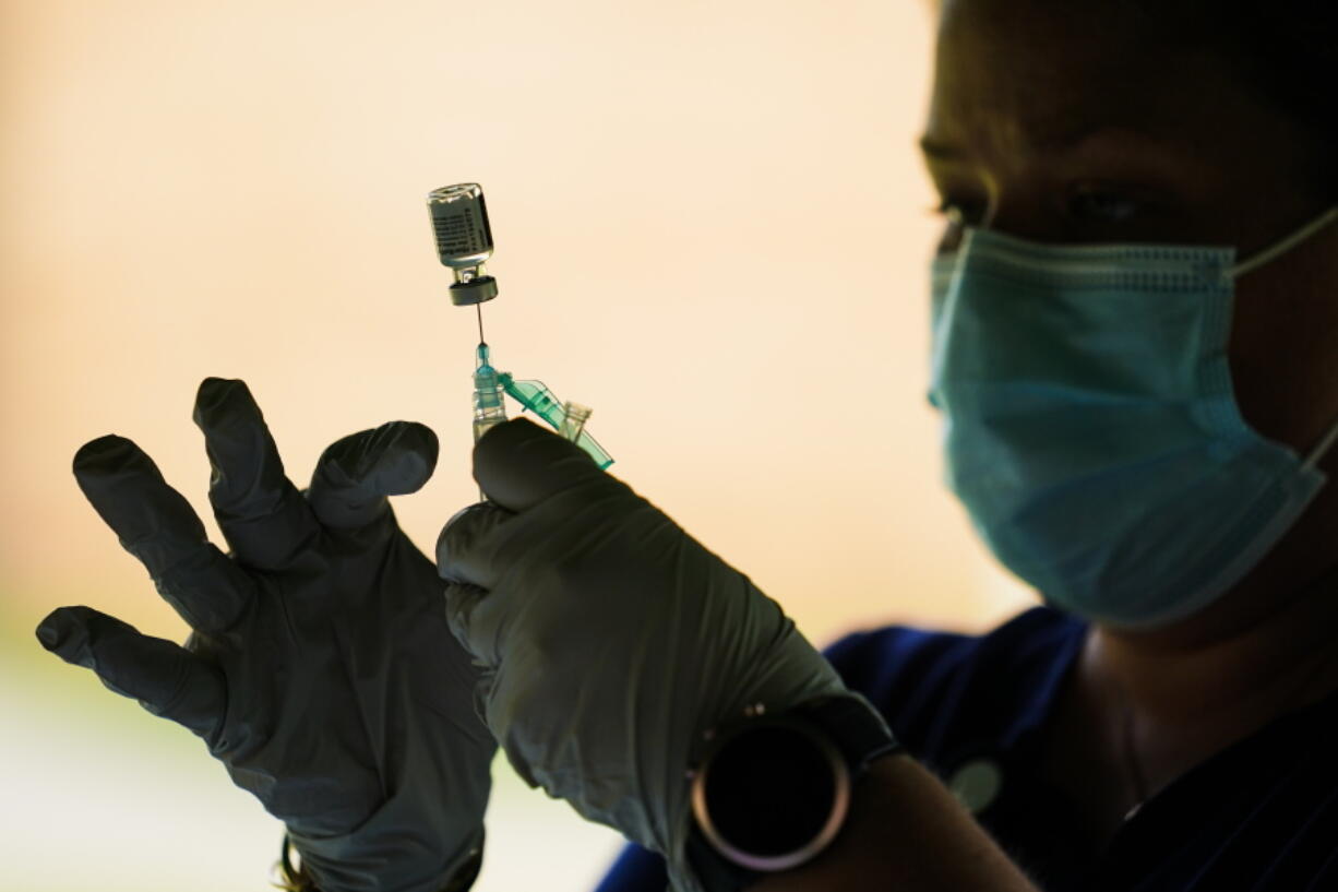 FILE - In this Sept. 14, 2021, file photo, a syringe is prepared with the Pfizer COVID-19 vaccine at a clinic at the Reading Area Community College in Reading, Pa.  Millions of U.S. workers now have a Jan. 4 deadline to get a COVID vaccine. The federal government on Thursday, Nov. 4, 2021 announced new vaccine requirements for workers at companies with more than 100 employees as well as workers at health care facilities that treat Medicare and Medicaid patients..