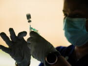 FILE - In this Sept. 14, 2021, file photo, a syringe is prepared with the Pfizer COVID-19 vaccine at a clinic at the Reading Area Community College in Reading, Pa.  Companies with at least 100 workers will be required to give employees paid time off to get vaccinated against COVID-19 and paid sick leave if they have side effects from the shots. That's according to a Biden administration official who spoke Monday, Nov. 1,  about pending vaccine-mandate rules from OSHA, the Occupational Safety and Health Administration.