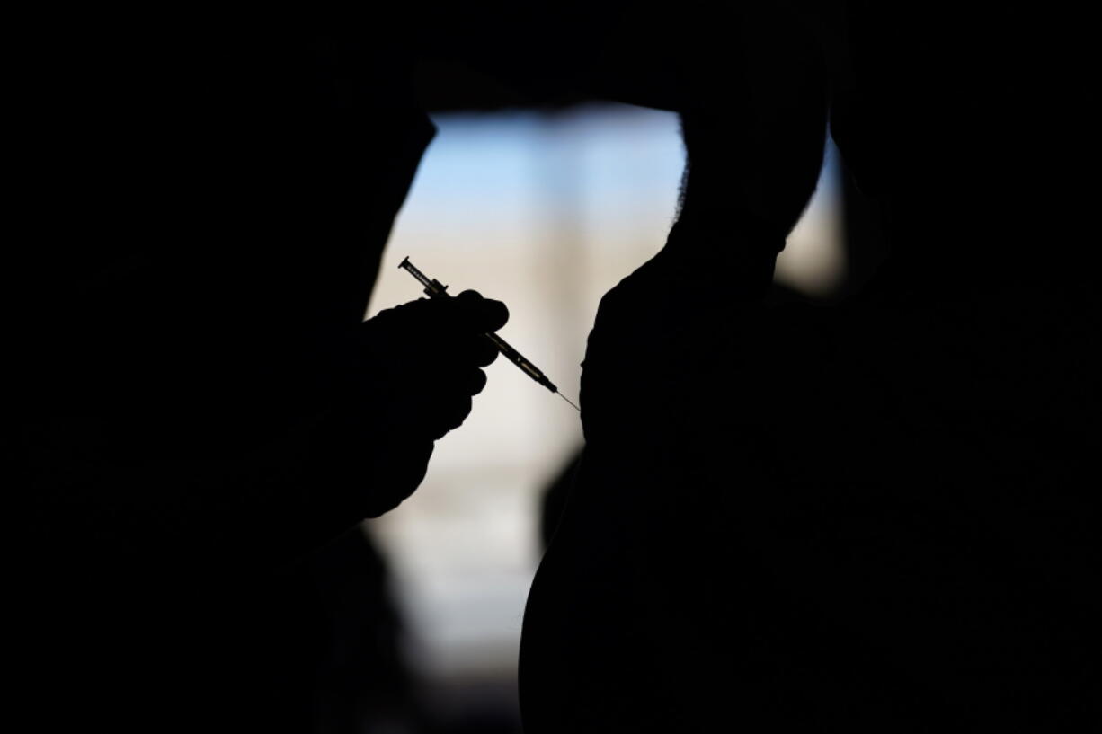 FILE - A man receives a COVID-19 vaccine at a vaccination site in Las Vegas. About 4 million federal workers, from FBI agents to Bureau of Prisons guards to U.S. Food and Drug Administration workers, are to be vaccinated by Nov. 22 under the president's executive order aimed at stopping the spread of the coronavirus.