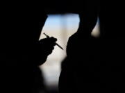 FILE - A man receives a COVID-19 vaccine at a vaccination site in Las Vegas. About 4 million federal workers, from FBI agents to Bureau of Prisons guards to U.S. Food and Drug Administration workers, are to be vaccinated by Nov. 22 under the president's executive order aimed at stopping the spread of the coronavirus.