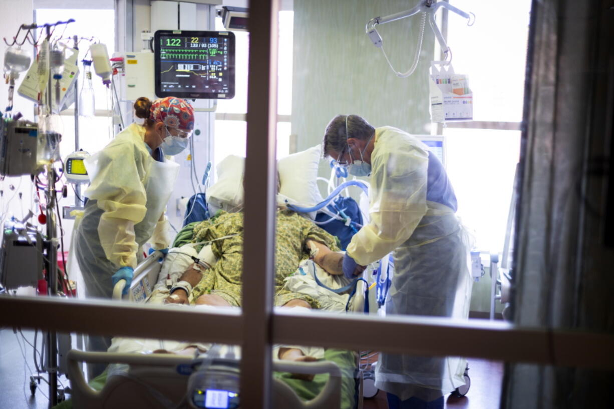 FILE - Dr. William Dittrich M.D. looks over a COVID-19 patient in the Medical Intensive care unit (MICU) at St. Luke's Boise Medical Center in Boise, Idaho, Aug. 31, 2021. The rate of COVID-19 hospitalizations and newly confirmed coronavirus cases has been dropping in Idaho, but the numbers are still high enough to leave hospitals overtaxed, Idaho Division of Public Health Administrator Elke Shaw-Tulloch said Tuesday, Nov. 2, 2021.