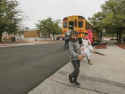 FILE - Kindergarteners who are learning remotely during the coronavirus pandemic pick up meals at a bus stop near their home in Santa Fe, N.M., on Sept. 9, 2020. The Santa Fe school district decided last week to close its doors Tuesday, Nov. 23, 2021, and pivot to remote learning in a bid to reduce virus outbreaks ahead of the Thanksgiving holiday.