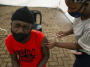 A man receives a dose of a vaccine at a COVID-19 vaccine centre, in Soweto, Monday, Nov. 29, 2021. The World Health Organization has urged countries not to impose flight bans on southern African nations due to concerns over the new omicron variant.