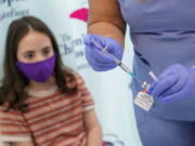 FILE - Jamie Onofrio Franceschini, 11, watches as RN Rosemary Lantigua prepares a syringe with her first dose of the Pfizer COVID-19 vaccine for children five to 12 years at The Children's Hospital at Montefiore, Nov. 3, 2021, in the Bronx borough of New York. The United States is steadily chipping away at vaccine hesitancy and driving down COVID-19 cases and hospitalizations to the point that schools, governments and corporations are lifting mask restrictions yet again.