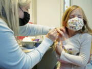 Shauna Andrus, left, a nurse volunteering at the University of Washington Medical Center, gives the first shot of the Pfizer COVID-19 vaccine to Emmy Slonecker, 7, Tuesday, Nov. 9, 2021, in Seattle. Last week, U.S. health officials gave the final signoff to Pfizer's kid-size COVID-19 shot, a milestone that opened a major expansion of the nation's vaccination campaign to children as young as 5. (AP Photo/Ted S.