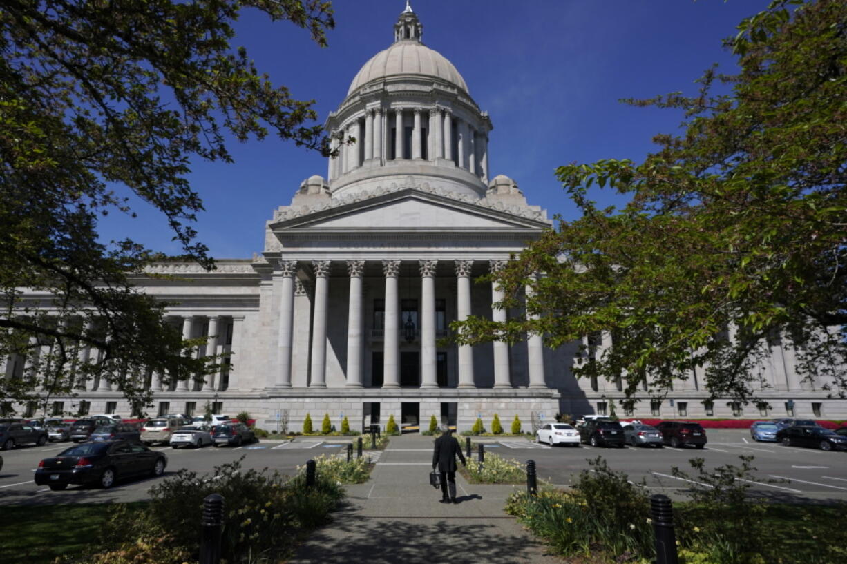 FILE - A person walks near the Legislative Building, Wednesday, April 21, 2021, at the Capitol in Olympia, Wash. Washington's redistricting commission failed to meet its deadline and on Tuesday, Nov. 16, kicked the job of creating new political maps to the state Supreme Court. The bipartisan commission had a deadline of 11:59 p.m. Monday to approve new boundaries for congressional and legislative districts following the 2020 census. (AP Photo/Ted S.