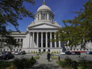 FILE - A person walks near the Legislative Building, Wednesday, April 21, 2021, at the Capitol in Olympia, Wash. Washington's redistricting commission failed to meet its deadline and on Tuesday, Nov. 16, kicked the job of creating new political maps to the state Supreme Court. The bipartisan commission had a deadline of 11:59 p.m. Monday to approve new boundaries for congressional and legislative districts following the 2020 census. (AP Photo/Ted S.