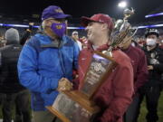 Washington State acting head coach Jake Dickert, right shakes hands with Washington Gov. Jay Inslee, left, after Inslee presented him with the Apple Cup Trophy after Washington State beat Washington 40-13 in an NCAA college football game, Friday, Nov. 26, 2021, in Seattle. (AP Photo/Ted S.