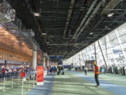 The exposed underside of the Portland International Airport roof hangs above travelers. The expanded terminal that is planned in the PDX Next project will include a new, curved roof.