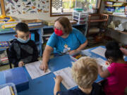 Julian Gomez, 5, left, works with teacher Sandy Becker, red mask, as he learns the letters of the alphabet at Jack and Jill House on Thursday morning. The day care is one of Clark County's 86 licensed child care centers.