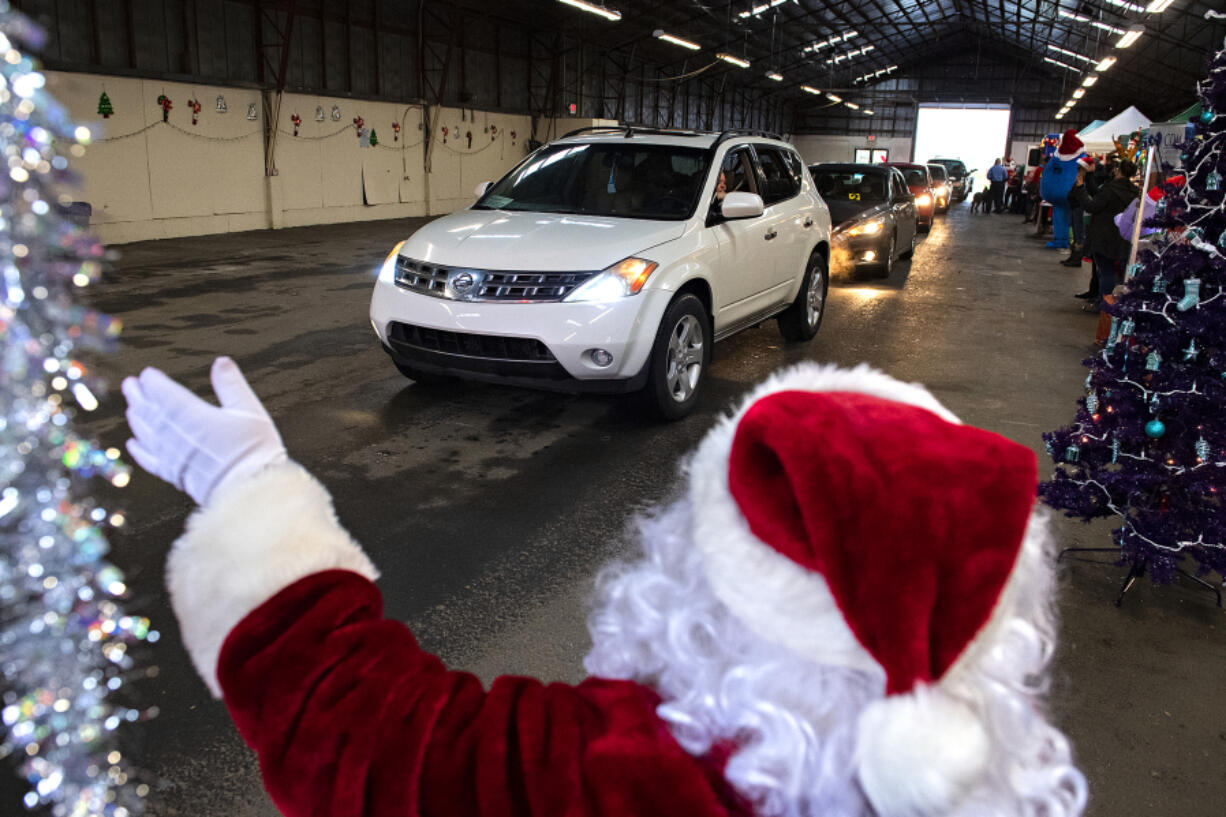 Motorists drive through the second annual Caregivers Christmas, hosted by the nonprofit Loving Them Forward, at the Clark County Event Center at the Fairgrounds on Tuesday morning. The organization was able to quadruple its efforts this year, a sign of increased giving this holiday season.