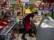 Salvador Larios, owner of Dulce Tentacion serves up fresh tamales for a customer Monday morning. At top, fresh tamales are sold to a customer at Dulce Tentacion on Monday morning. The shop has the necessary permits to make and sell tamales, but other tamale makers say high permitting costs for their seasonal treat has pushed them into the shadow economy.