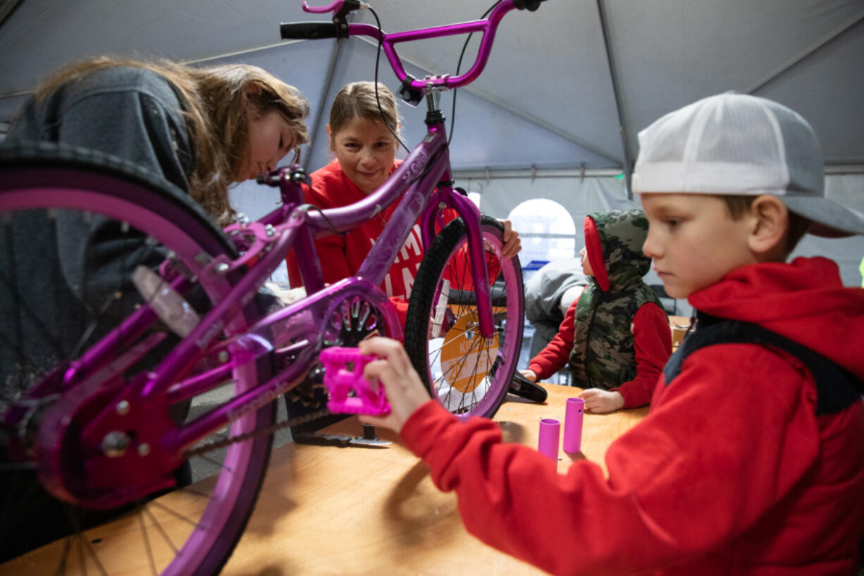 From left: Volunteers Carlie Palma, Sheina Martin, Brady Jones, 6, and Brody Jones, 8, assemble bicycles for children in need during the 11th annual Scott Campbell Christmas Promise at Taylor Transport in Vancouver on Saturday.