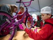 From left: Volunteers Carlie Palma, Sheina Martin, Brady Jones, 6, and Brody Jones, 8, assemble bicycles for children in need during the 11th annual Scott Campbell Christmas Promise at Taylor Transport in Vancouver on Saturday.